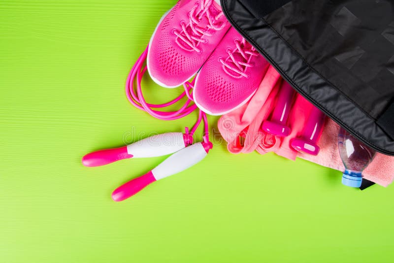 Rosa färgkläder och tillbehören för kondition, en flaska av vatten, i sportar hänger löst, på ett ljus - grön bakgrund royaltyfria foton Rosa färgkläder och tillbehören för kondition, en flaska av vatten, i sportar hänger löst, på ett ljus - grön bakgrund royaltyfria foton