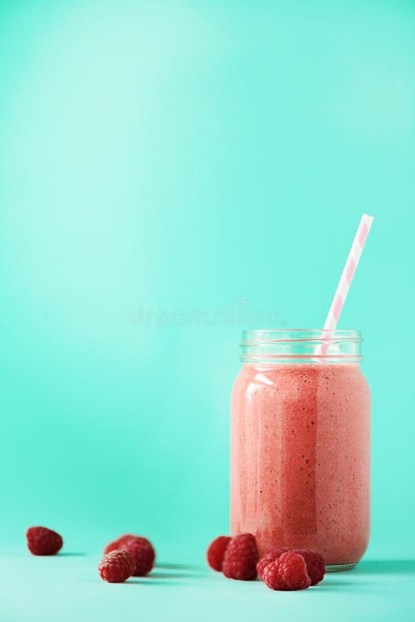 Rosa hallonmilkshake i den glass kruset på blå bakgrund med kopieringsutrymme Sommarmatbegreppet, strikt vegetarian bantar Rosa f royaltyfri foto Rosa hallonmilkshake i den glass kruset på blå bakgrund med kopieringsutrymme Sommarmatbegreppet, strikt vegetarian bantar Rosa f royaltyfri foto