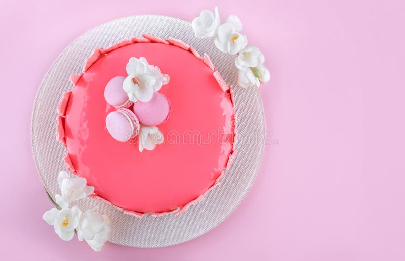 Rosa Kremeiskuchen mit der Spiegelglasur verziert mit Makronen, Blumen f?r alles Gute zum Geburtstag auf rosa Feiertagshintergrun