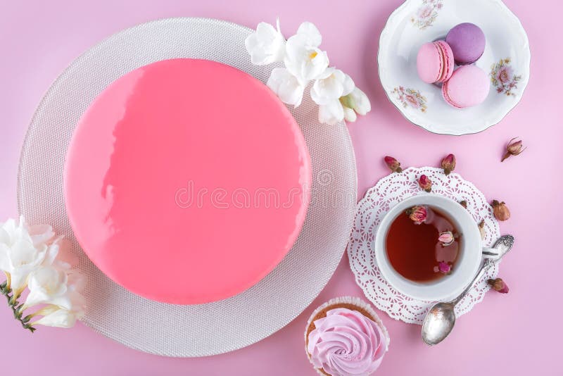Rosa Kremeiskuchen mit der Spiegelglasur verziert mit Makronen, Blumen für alles Gute zum Geburtstag auf rosa Feiertagshintergrun