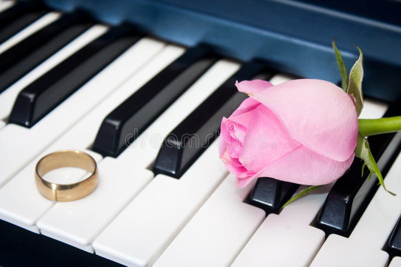 Pink rose and golden ring on the piano keyboard. Pink rose and golden ring on the piano keyboard.