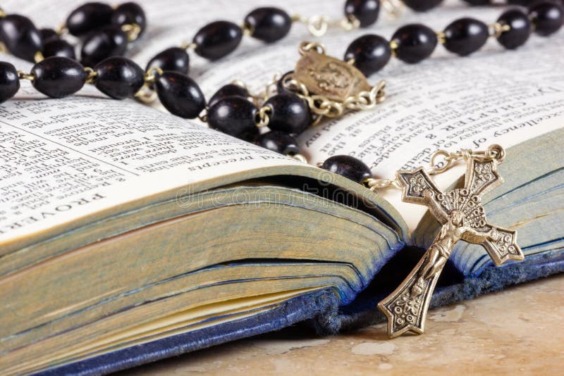 Rosary beads and cross lying on an open page of the bible. Rosary beads and cross lying on an open page of the bible.