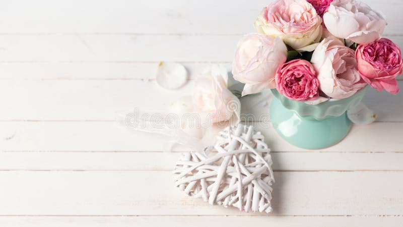Rosas en colores pastel en florero de la turquesa y corazón decorativo en el wo blanco imagen de archivo libre de regalías Rosas en colores pastel en florero de la turquesa y corazón decorativo en el wo blanco imagen de archivo libre de regalías