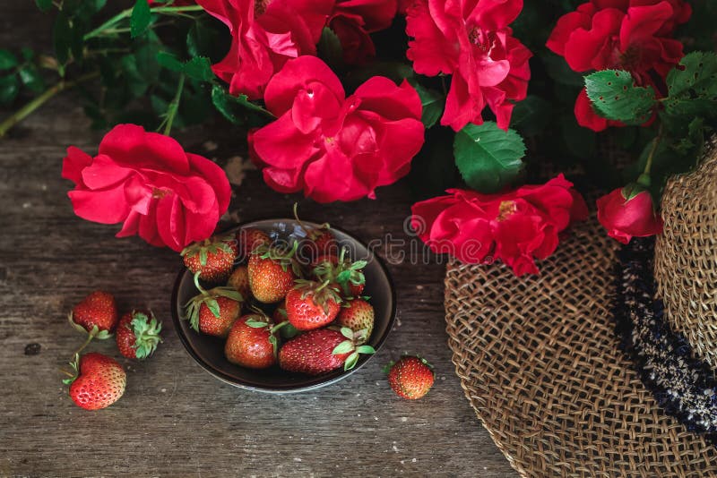 Rosas rojas, fresas y un sombrero en una tabla vieja fotografía de archivo Rosas rojas, fresas y un sombrero en una tabla vieja fotografía de archivo