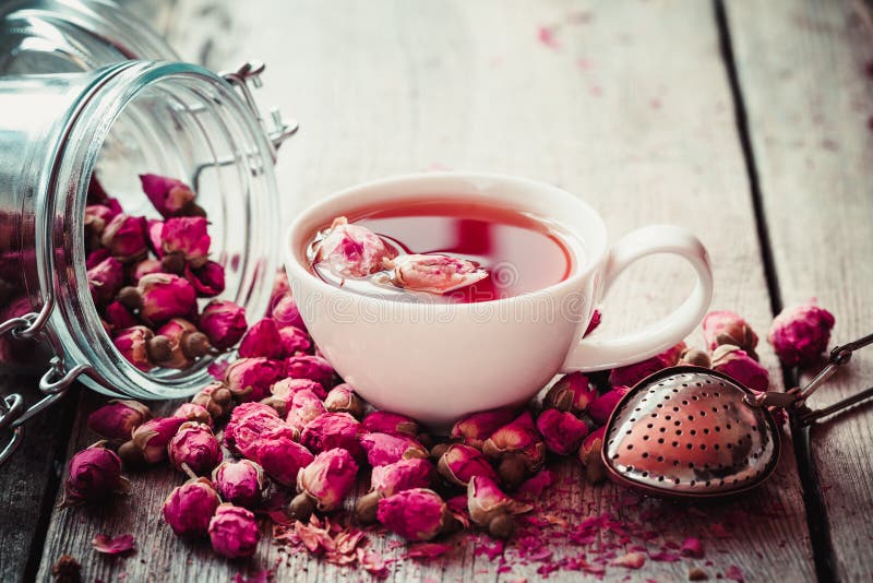 Rose buds tea, tea cup, strainer and glass jar with rosebuds