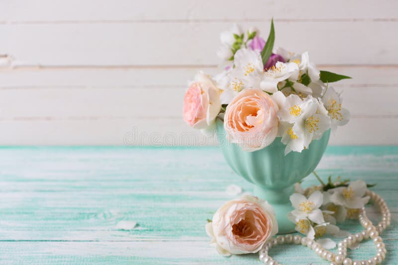 Pastel roses and jasmine flowers in vase on turquoise wooden background. Place for text. Selective focus. Pastel roses and jasmine flowers in vase on turquoise wooden background. Place for text. Selective focus.