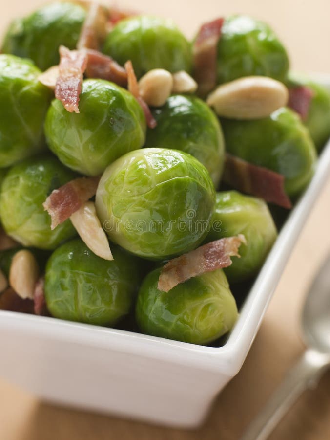 Rosenkohl mit gebratenem Speck und Mandeln stockbilder