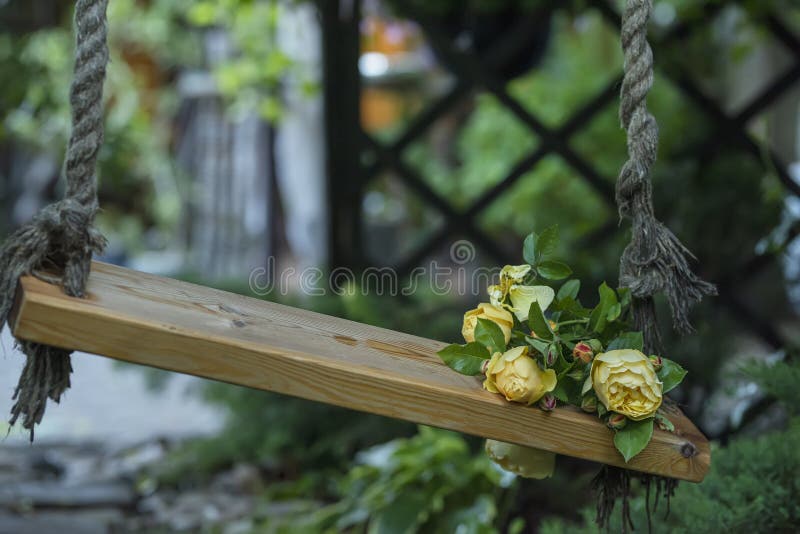 Rosenstrauß auf einer hübschen Holzschwinge im Garten lizenzfreie stockfotografie