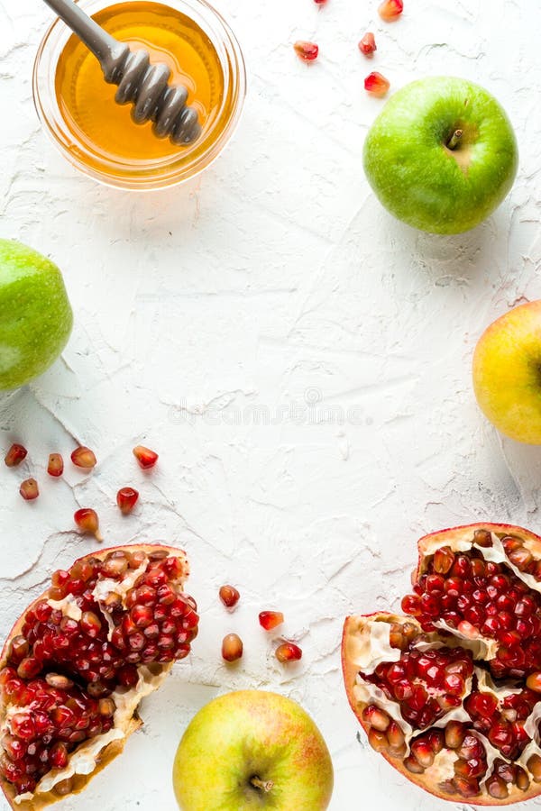 Rosh Hashanah frame of grains of pomegranate, honey and apples on a white background