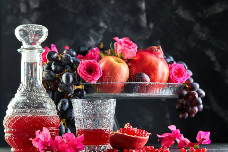Rosh hashanah jüdisches Feiertagskonzept Neujahr. Stillleben von frischen Herbstfrüchten und Granatapfelsaft in einem Dekantiergef