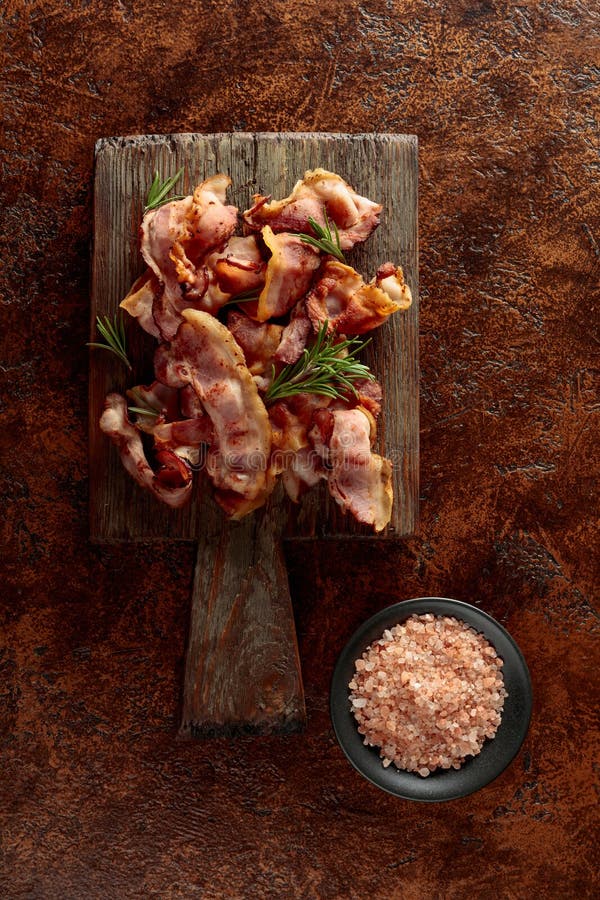 Rosmarin mit gebratenem Speck und rosa Salz auf braunem Hintergrund stockfotos