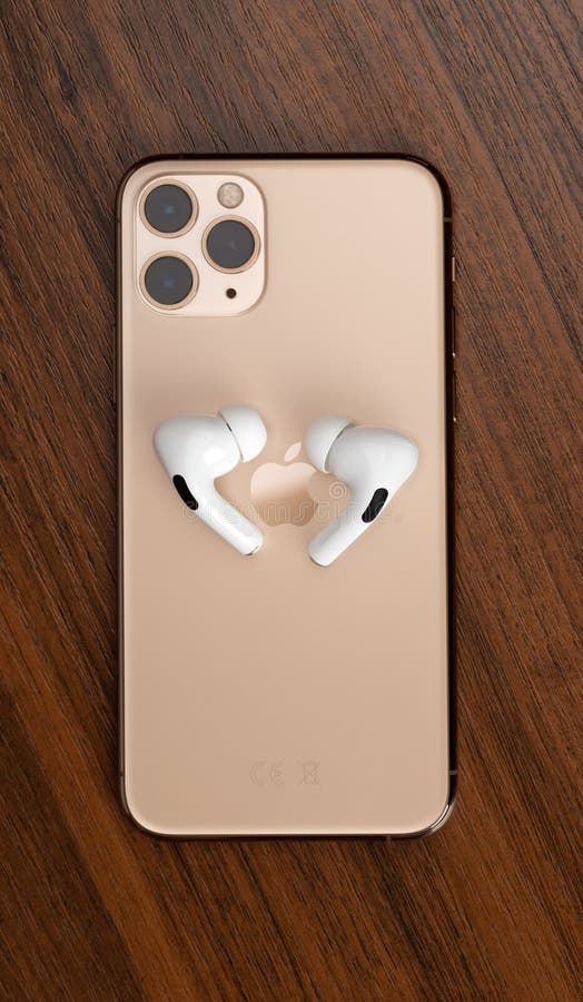 Apple AirPods Pro and iPhone 11 Pro on a wooden table. Wireless headphones and smartphone
