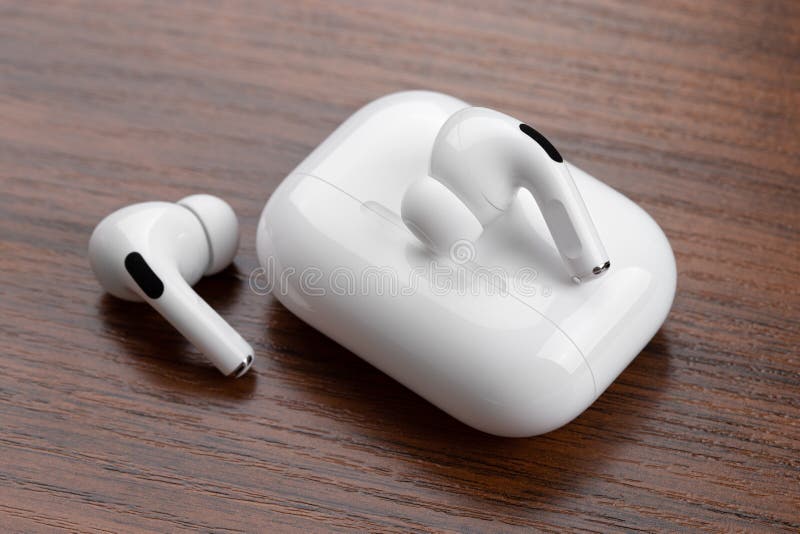 Apple AirPods Pro on a wooden table. Wireless headphones and charging case close-up