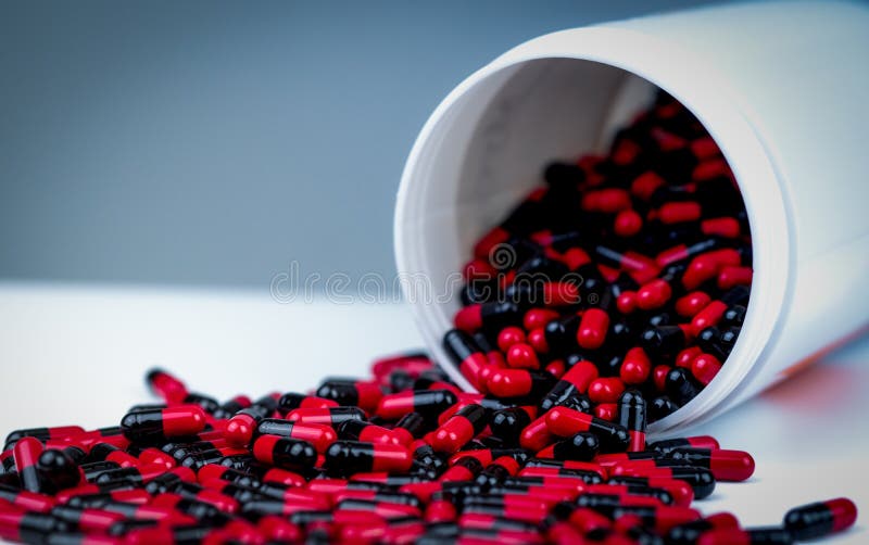 Rot-schwarze antibiotische Kapselpillen werden aus weißem Plastikflaschenbehälter heraus verschüttet viele Flaschen Medizin Versc stockbild Rot-schwarze antibiotische Kapselpillen werden aus weißem Plastikflaschenbehälter heraus verschüttet viele Flaschen Medizin Versc stockbild