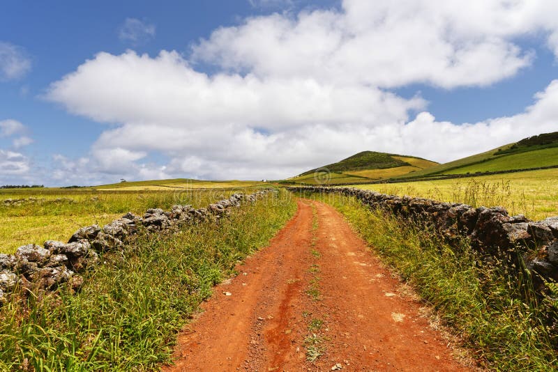 Rote Fahrstraße in einer hügeligen Landschaft lizenzfreie stockfotos Rote Fahrstraße in einer hügeligen Landschaft lizenzfreie stockfotos