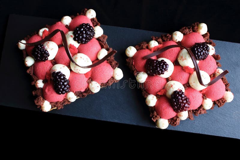 Rote Johannisbeerkremeis- und -brombeerblätterteignachtische mit gepeitschten ganache und Schokoladenspiralendekorationen, Drauf stockbilder Rote Johannisbeerkremeis- und -brombeerblätterteignachtische mit gepeitschten ganache und Schokoladenspiralendekorationen, Drauf stockbilder