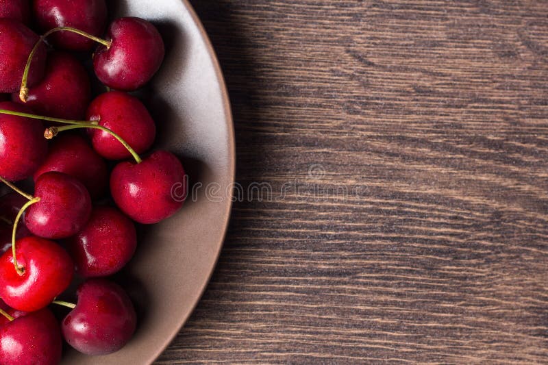 Rote Kirschen auf einer braunen Platte auf einem Holztisch Sommernahrung, gesunde Ernährung Organisch, vegetarisch, strenger Vege lizenzfreies stockfoto Rote Kirschen auf einer braunen Platte auf einem Holztisch Sommernahrung, gesunde Ernährung Organisch, vegetarisch, strenger Vege lizenzfreies stockfoto
