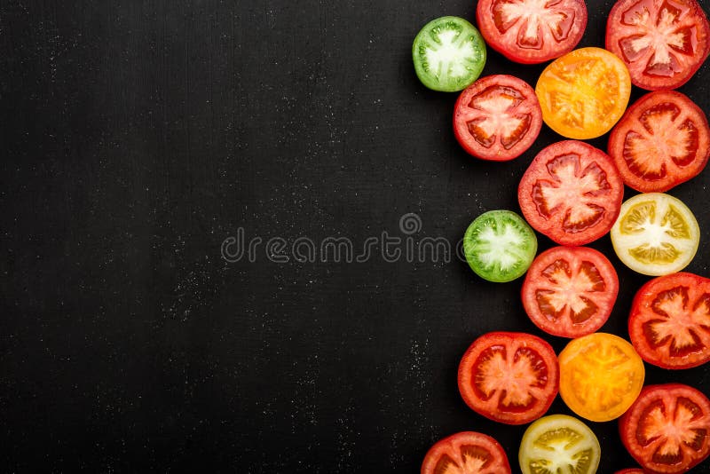 Rote Tomaten von verschiedenen Farben schnitten zur Hälfte Saftiges Gemüse auf schwarzem Hintergrund lizenzfreie stockbilder