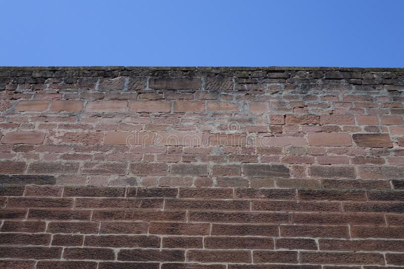 Red brickstone wall under blue sky &#x28;low angle view&#x29;, use: background, wallpaper, texture, Kaiserslautern, RLP, Germany. Red brickstone wall under blue sky &#x28;low angle view&#x29;, use: background, wallpaper, texture, Kaiserslautern, RLP, Germany