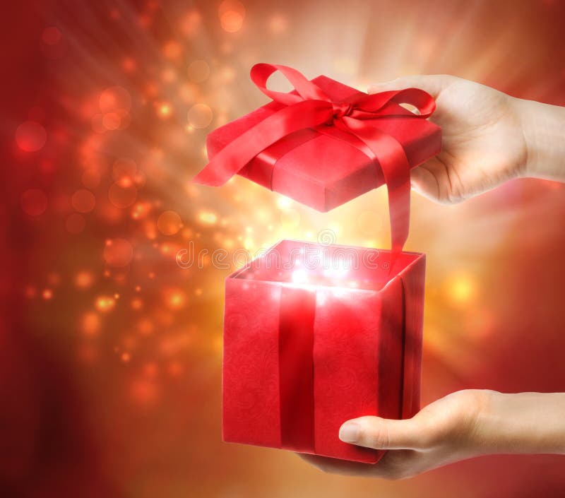Woman holding a red gift box on a bright holiday lights background. Woman holding a red gift box on a bright holiday lights background