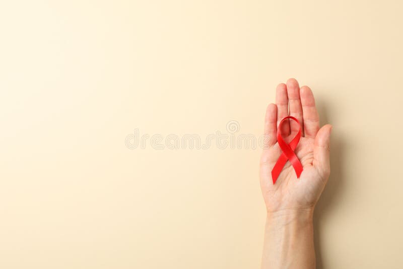 Rotes Bewusstseinsband des weiblichen Handgriffs auf Farbhintergrund lizenzfreies stockfoto