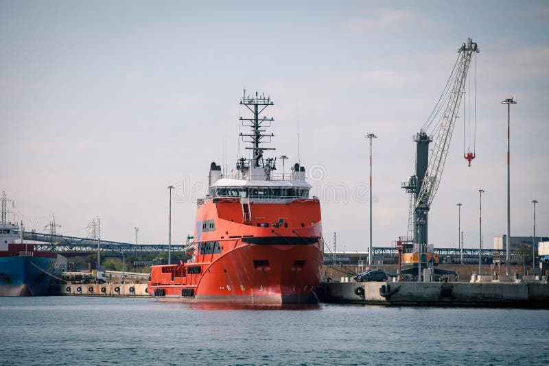 Rotes Frachtschiff vor Hafenanlagen und -kränen stockbild Rotes Frachtschiff vor Hafenanlagen und -kränen stockbild