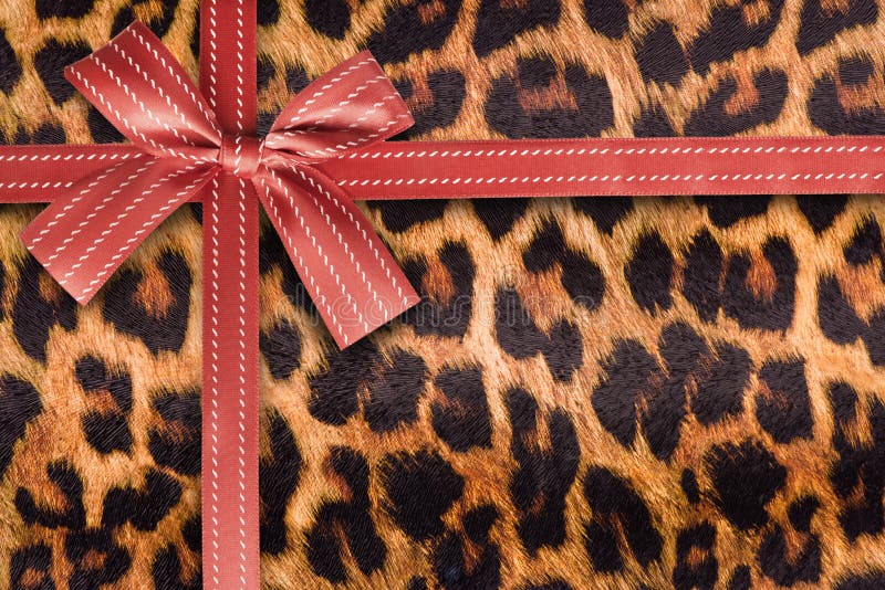 Rotes Geschenkband auf einer Leopardmusterbeschaffenheit lizenzfreie stockbilder