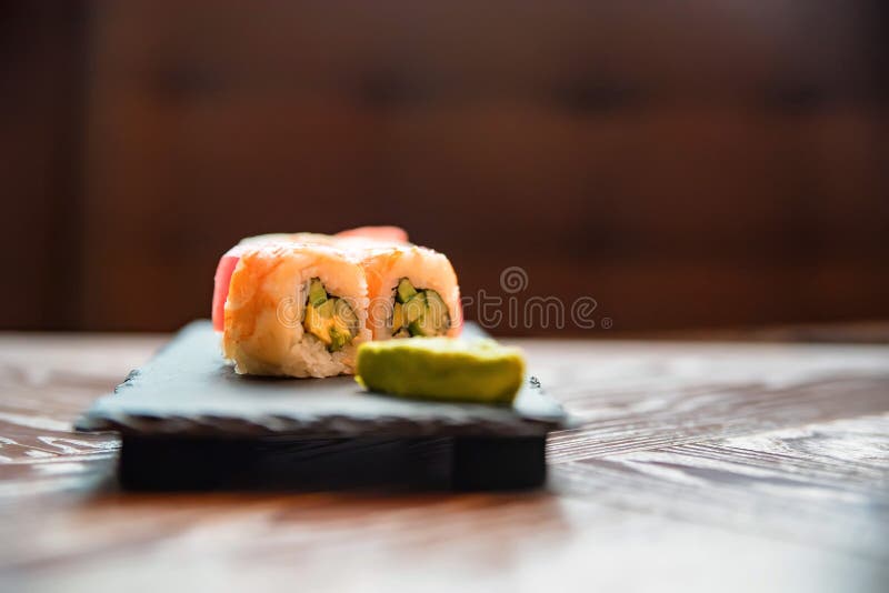 Rotolo di sushi dell'arcobaleno con wasabi sulla fine del vassoio su immagini stock Rotolo di sushi dell'arcobaleno con wasabi sulla fine del vassoio su immagini stock