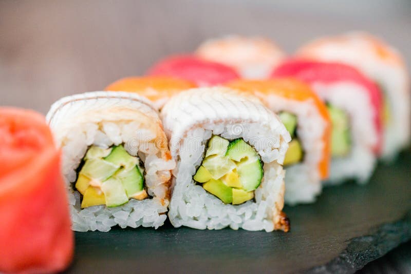 Rotolo di sushi dell'arcobaleno sul vassoio con la fine dello zenzero su immagini stock Rotolo di sushi dell'arcobaleno sul vassoio con la fine dello zenzero su immagini stock