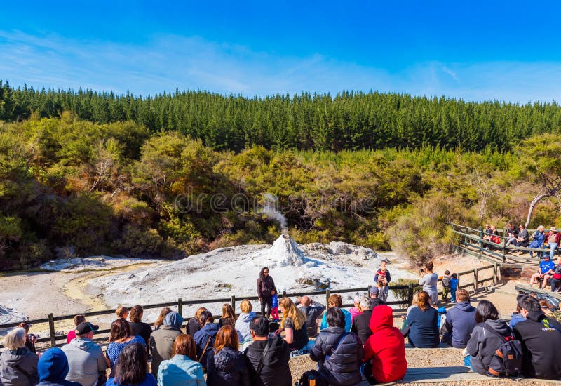 ROTORUA, NEUSEELAND - 10. OKTOBER 2018: Mengen, die sitzen, um tägliche Eruption von Dame Knox Geyser in Wai-o-Tapu aufzupassen stockbild ROTORUA, NEUSEELAND - 10. OKTOBER 2018: Mengen, die sitzen, um tägliche Eruption von Dame Knox Geyser in Wai-o-Tapu aufzupassen stockbild