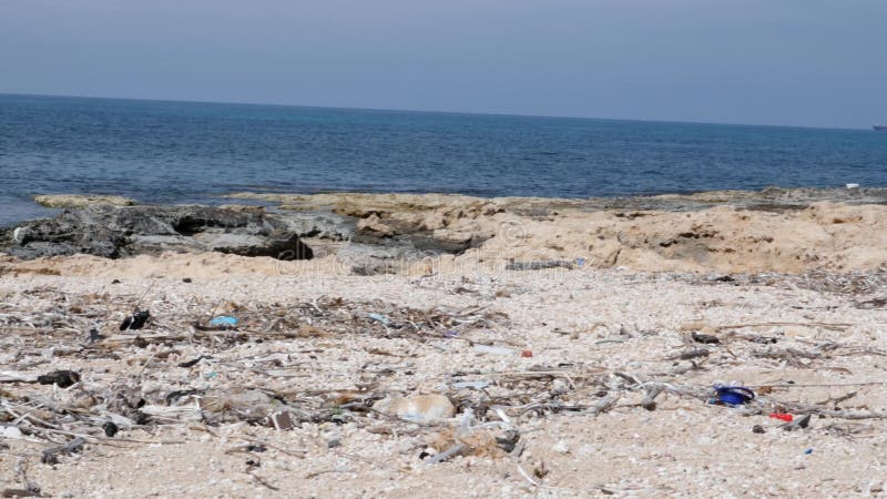 Rotsachtig strand met afval en huisvuil Milieuvervuilingconcept