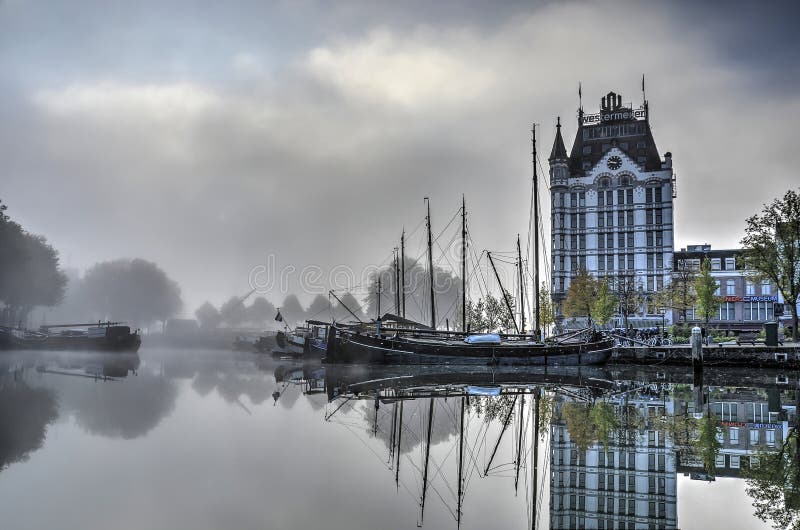 Rotterdam, The Netherlands, October 21, 2016: historic skyscraper the White House and historic barges reflect in the mirrorlike surface of the Old Harbour on a misty day. Barges rotterdam stock images, royalty-free photos and pictures