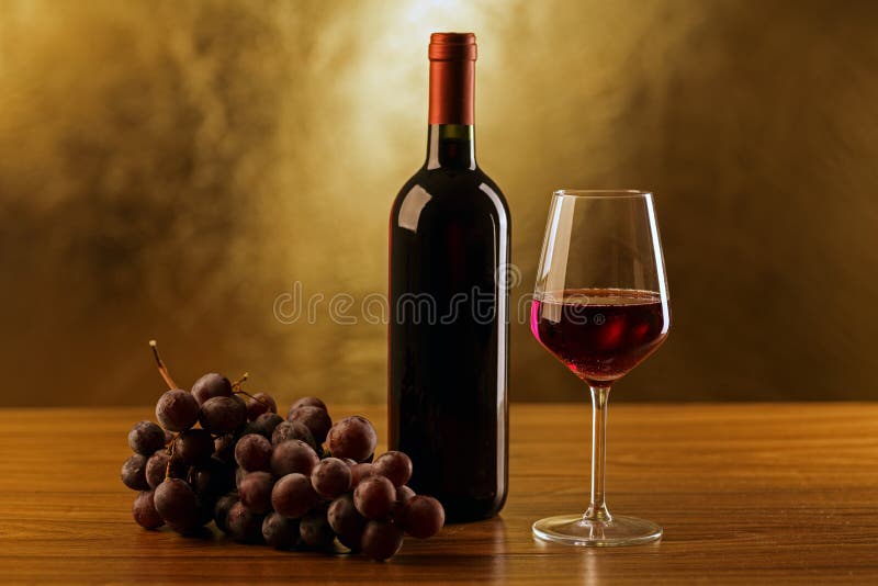 Rotweinflaschen mit Glas und Trauben auf Holztisch- und Goldhintergrund stockbild Rotweinflaschen mit Glas und Trauben auf Holztisch- und Goldhintergrund stockbild