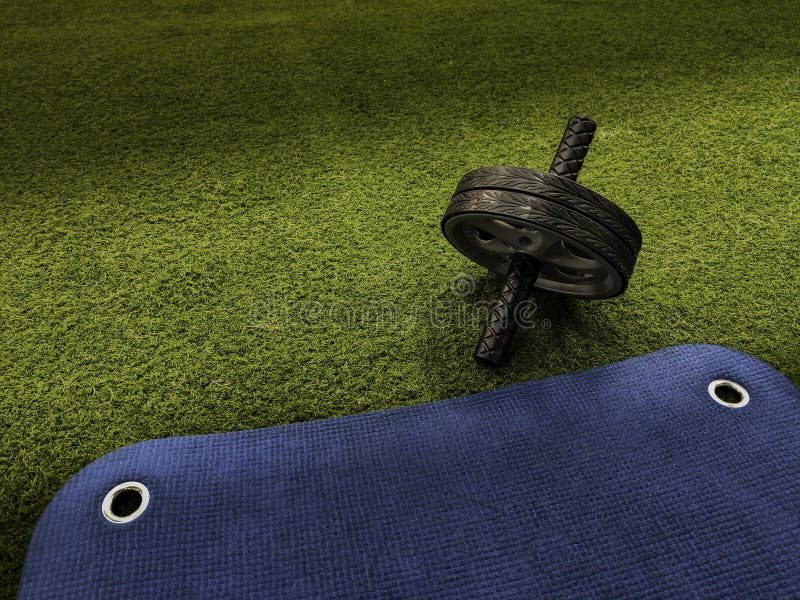Roue d'ABS sur l'herbe artificielle verte et le tapis s'exerçant bleu photo stock Roue d'ABS sur l'herbe artificielle verte et le tapis s'exerçant bleu photo stock