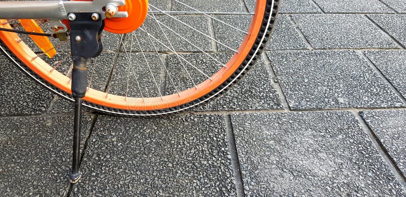 Roue à moitié orange de bicyclette et de support noir sur le plancher rugueux noir ou gris avec l'espace de copie image libre de droits Roue à moitié orange de bicyclette et de support noir sur le plancher rugueux noir ou gris avec l'espace de copie image libre de droits