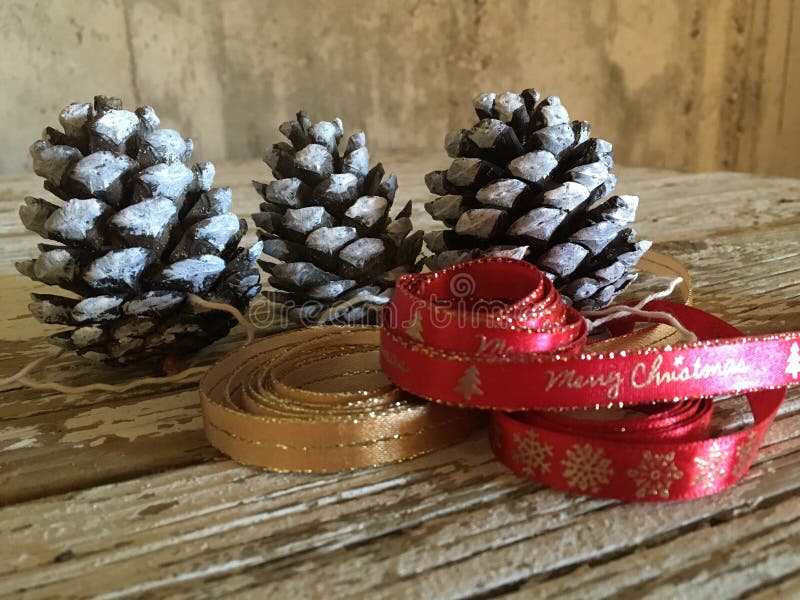 Rouge et ribboon d'or avec des cônes de pin sur le bois pour le cadeau de Noël images libres de droits Rouge et ribboon d'or avec des cônes de pin sur le bois pour le cadeau de Noël images libres de droits