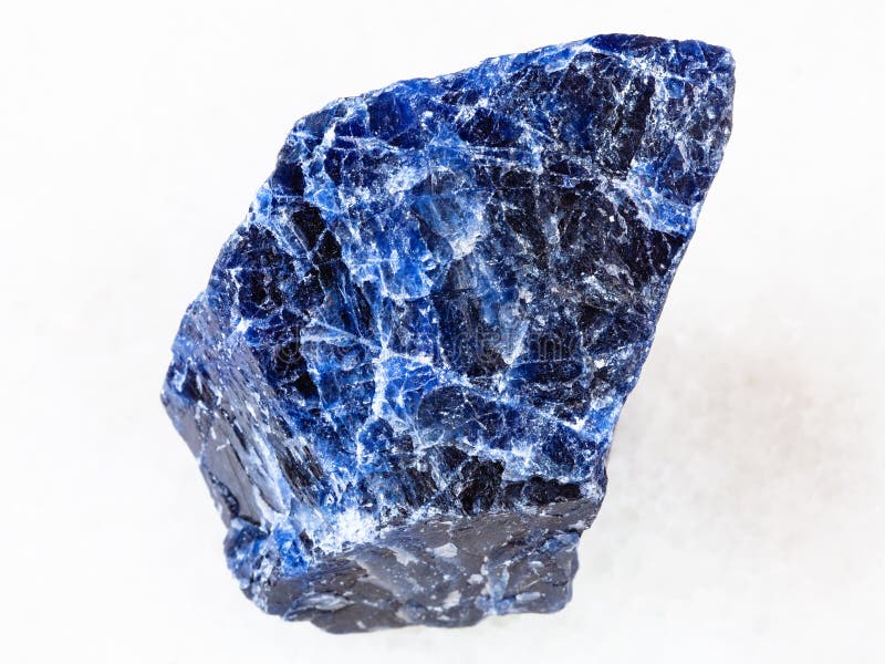 Macro shooting of natural rock specimen - rough Sodalite gemstone on white marble background