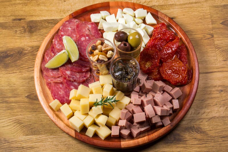 Round board with various antipasti appetizers. Cheese, salami, olives, nut mix and sun-dried tomatoes. top view royalty free stock photography Round board with various antipasti appetizers. Cheese, salami, olives, nut mix and sun-dried tomatoes. top view royalty free stock photography