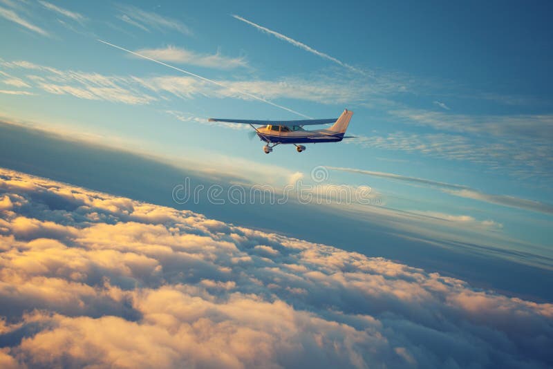 The round curve of the earth covered by golden clouds and a sall single engine airplane flying in the sunset