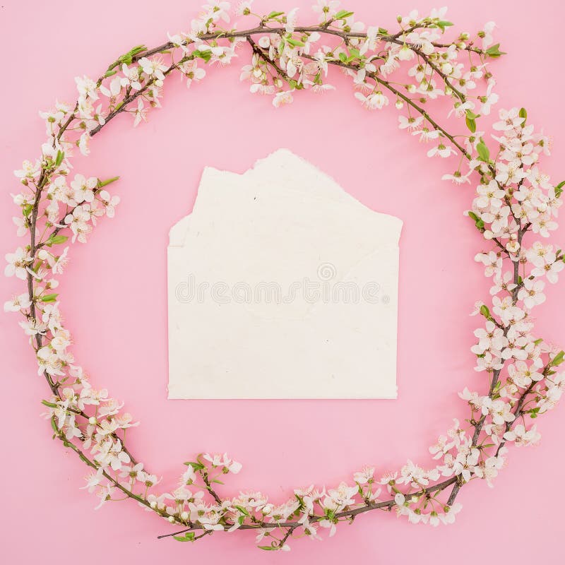 Round frame made of spring flowers and paper vintage envelope on pink background. Flat lay stock photo Round frame made of spring flowers and paper vintage envelope on pink background. Flat lay stock photo