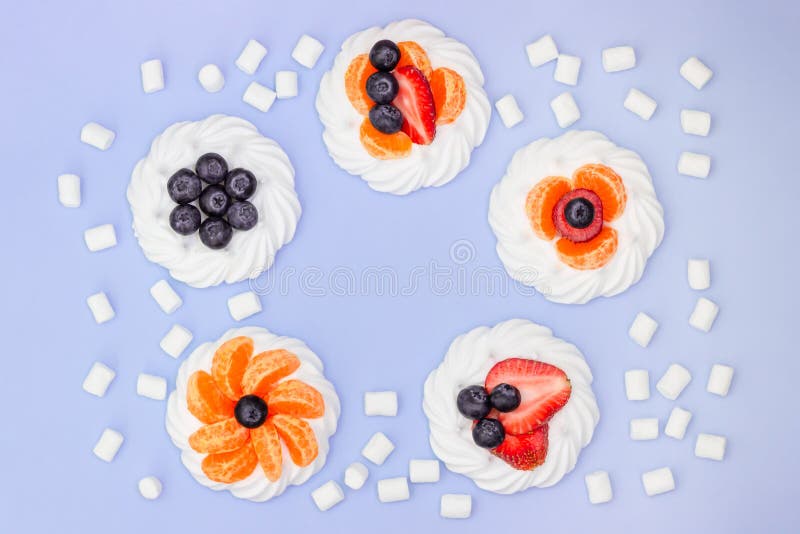 Round frame of meringue with blueberries, strawberries, marshmallow and tangerines on a lavender background. Top view stock image Round frame of meringue with blueberries, strawberries, marshmallow and tangerines on a lavender background. Top view stock image