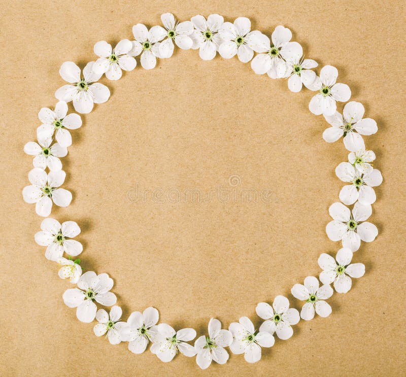 Round frame wreath made of white spring flowers on brown paper background. Top view royalty free stock photography Round frame wreath made of white spring flowers on brown paper background. Top view royalty free stock photography