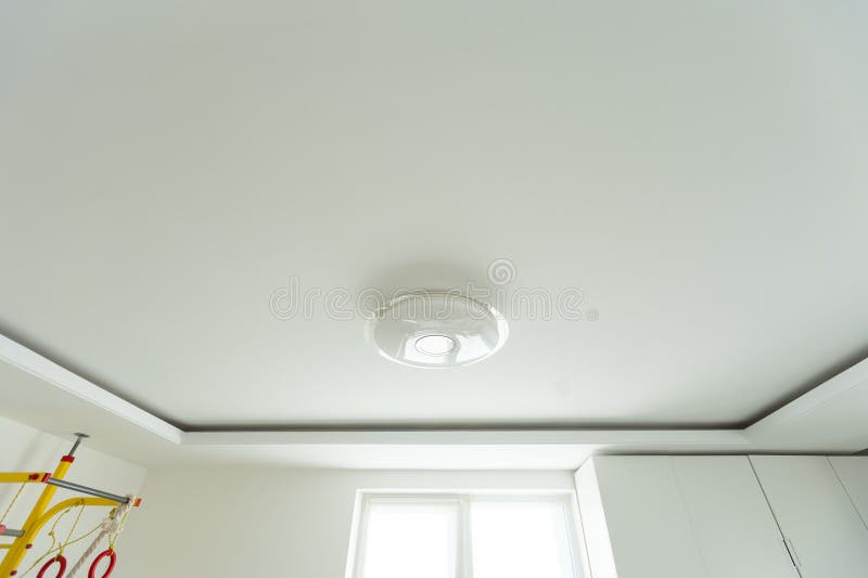 Round, minimalist, simple lamp on a white ceiling. A lamp that does not attract attention stock image