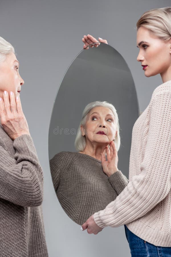 Cute senior mature woman looking in the mirror
