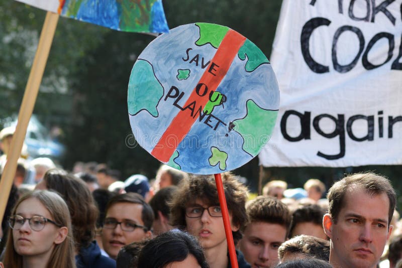 Round protest sign in the shape of planet earth saying `Save our planet` held up by young people during Global Climate Strike even