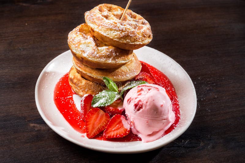 Round puffy waffles with strawberry ice cream with powdered sugar and with strawberry syrup stock photo Round puffy waffles with strawberry ice cream with powdered sugar and with strawberry syrup stock photo