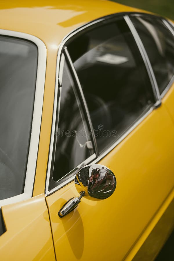 Close up shot of a round rear view mirror on a vintage yellow car