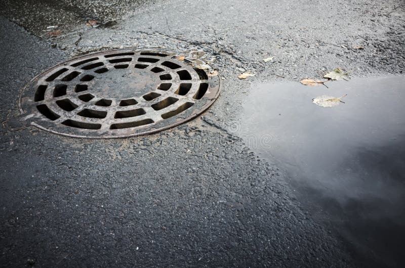 Round sewer manhole cover in urban asphalt