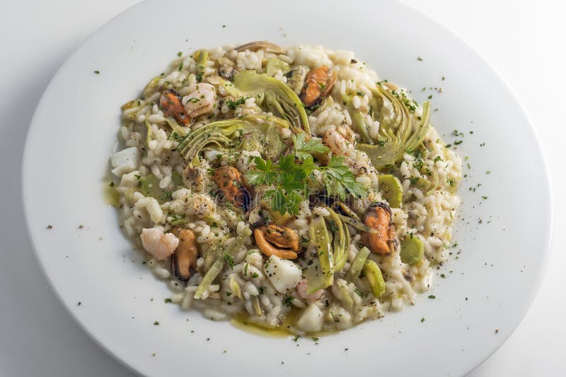 Round white dish of risotto with artichokes and seafood isolated on white background