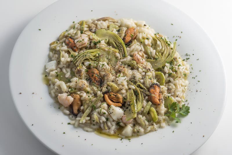 Round white dish of risotto with artichokes and seafood isolated on white background